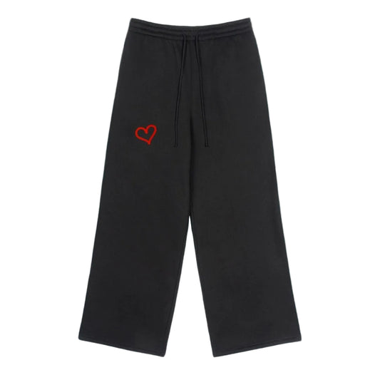 Black sweatpants with a red heart logo on a solid background