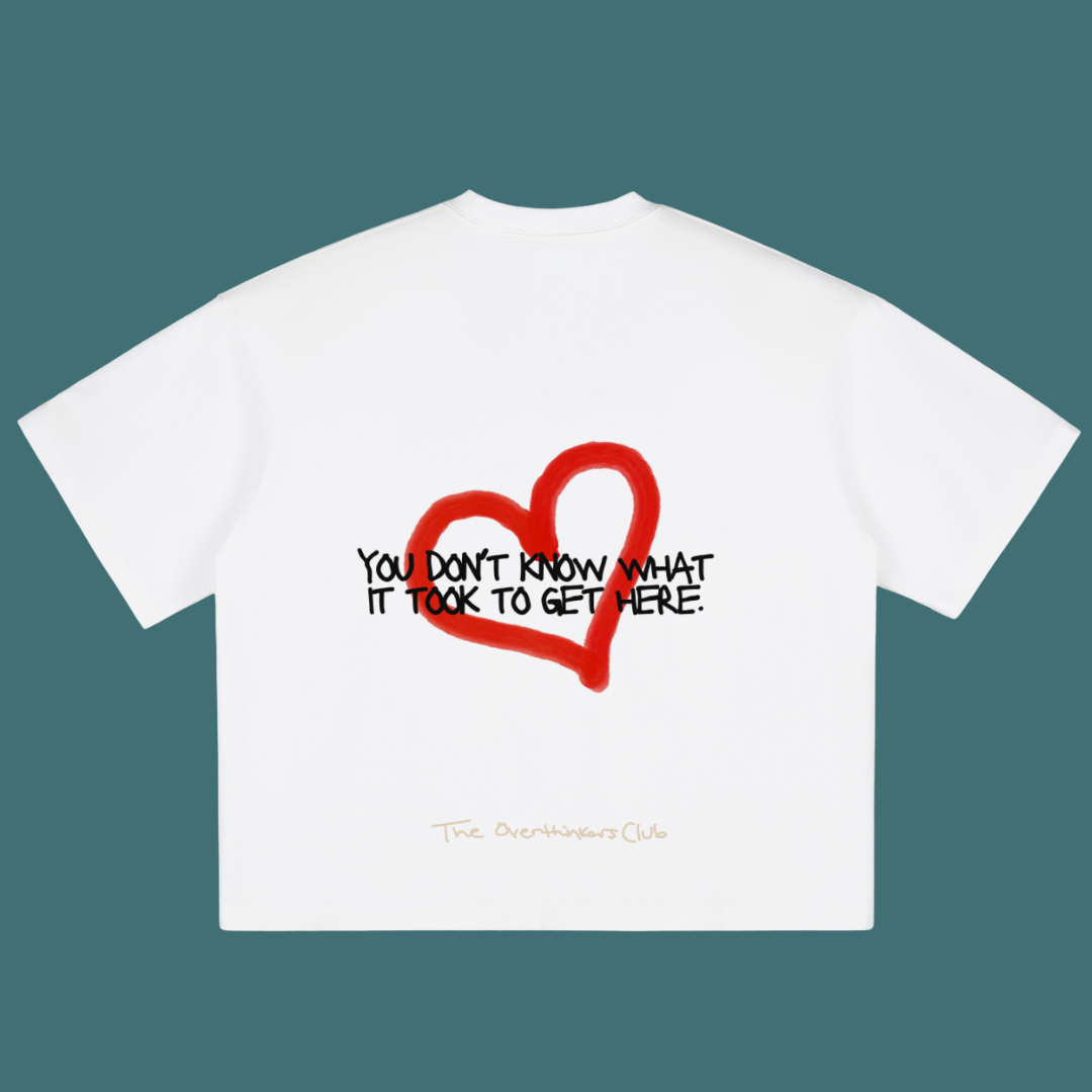 White t-shirt with red heart and black text on a teal background