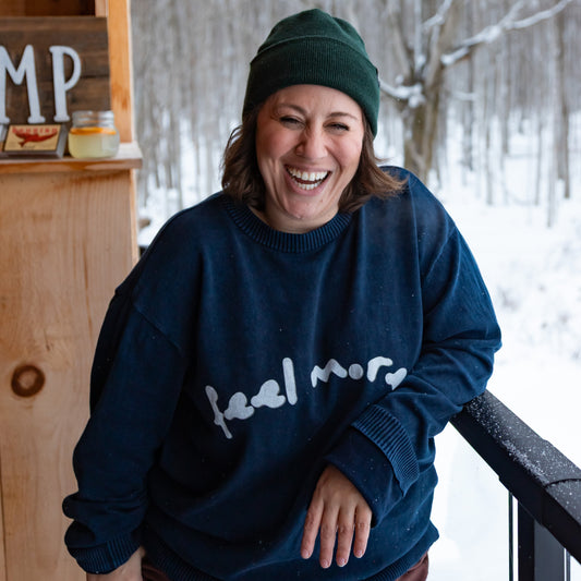 Person wearing a navy blue sweatshirt with text, standing in a snowy outdoor setting.