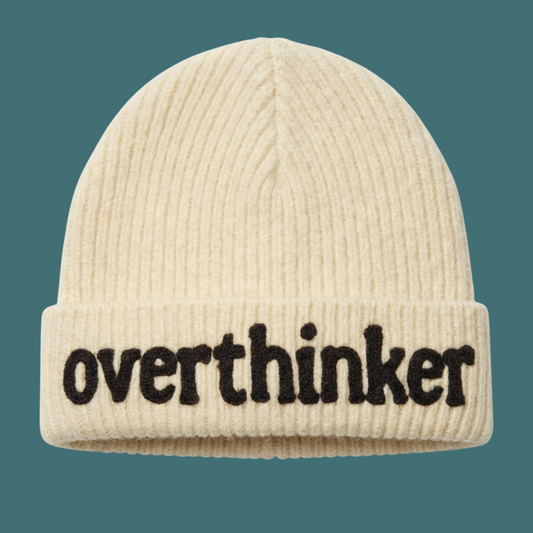Beige beanie with 'overthinker' text on a teal background