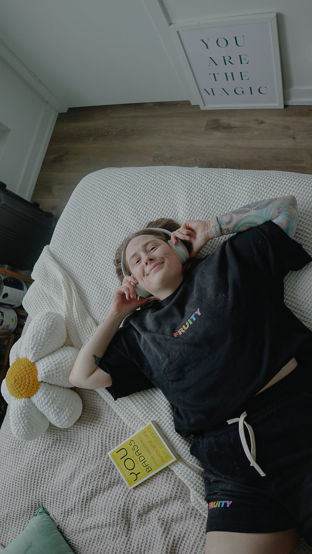 Person lying on a bed with headphones on, smiling.