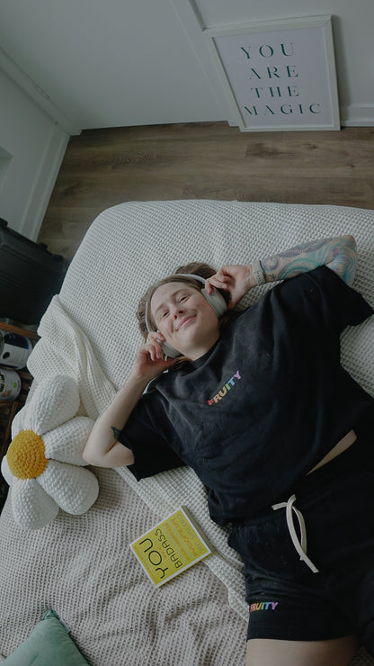 Person lying on a bed with headphones on, smiling.