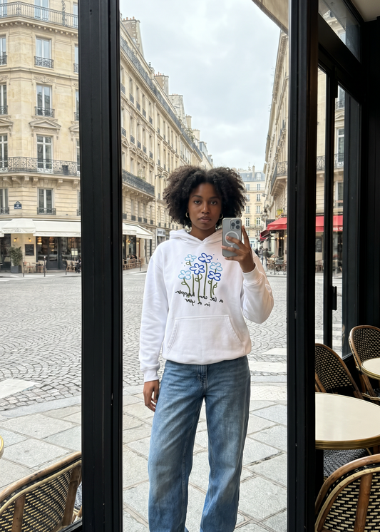 Person taking a selfie in a city street with buildings and cafes in the background