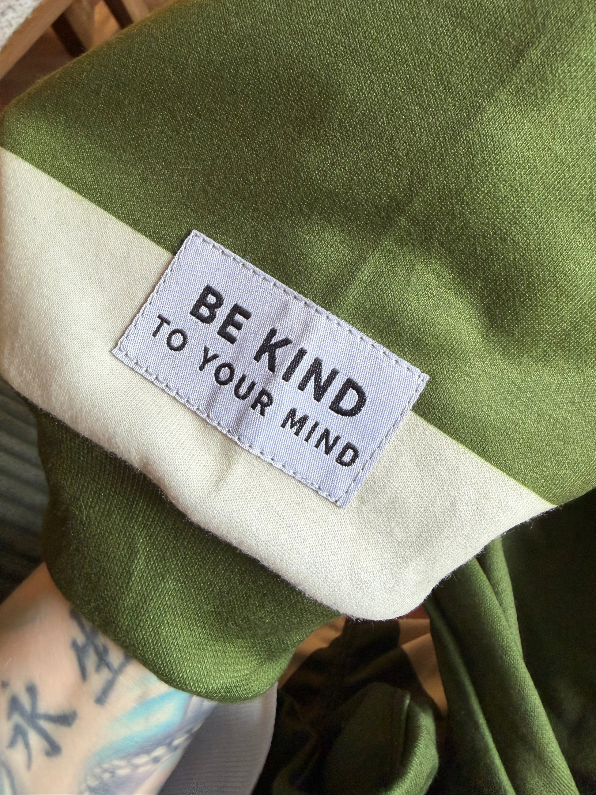 Green fabric with a label reading 'Be Kind to Your Mind' on a blurred background
